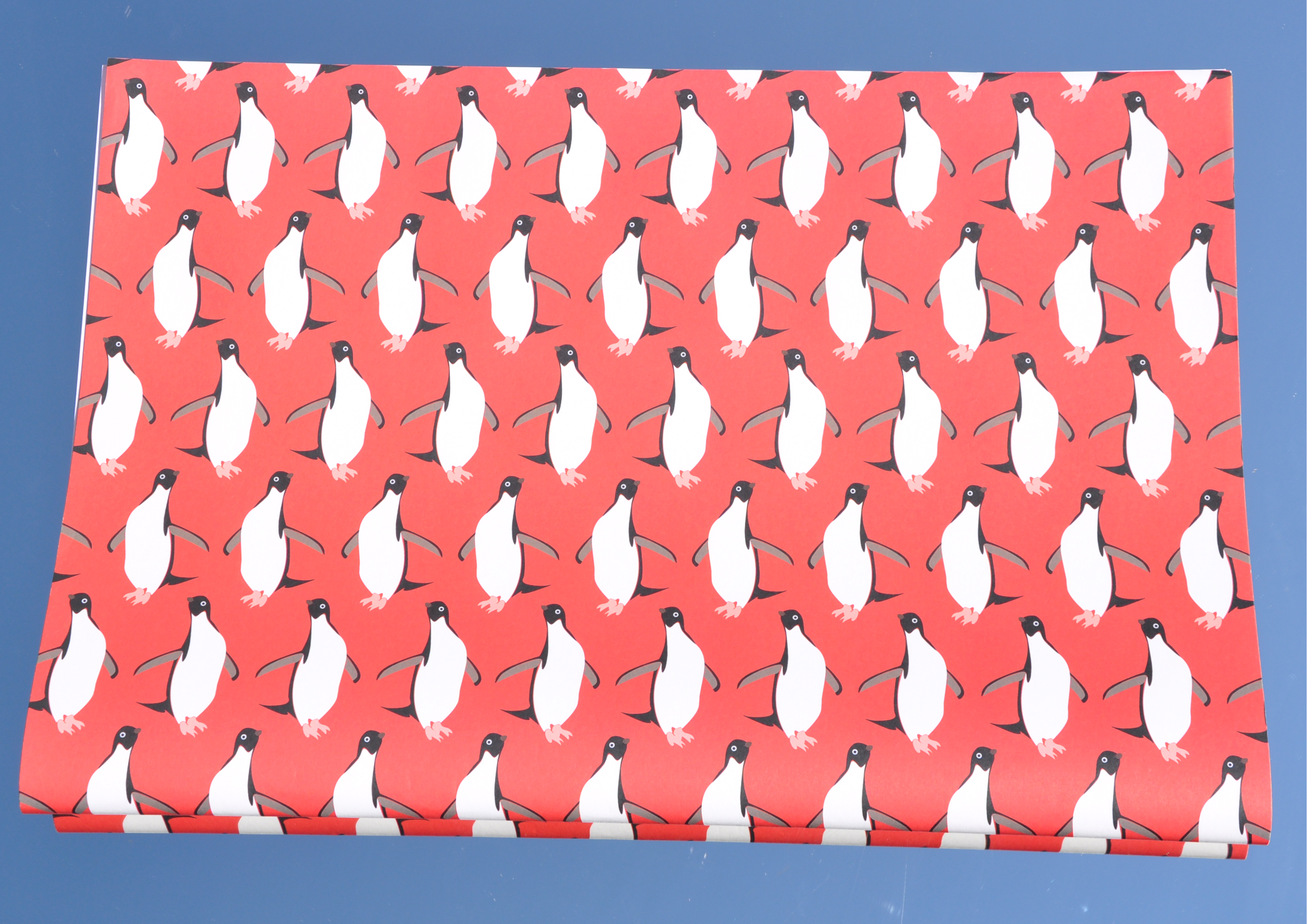 Adélie Pinguine - Geschenkpapier mit rotem Hintergrund